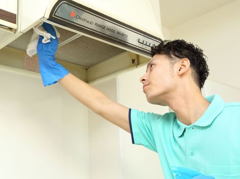 キッチンのレンジフードを掃除する男性スタッフ